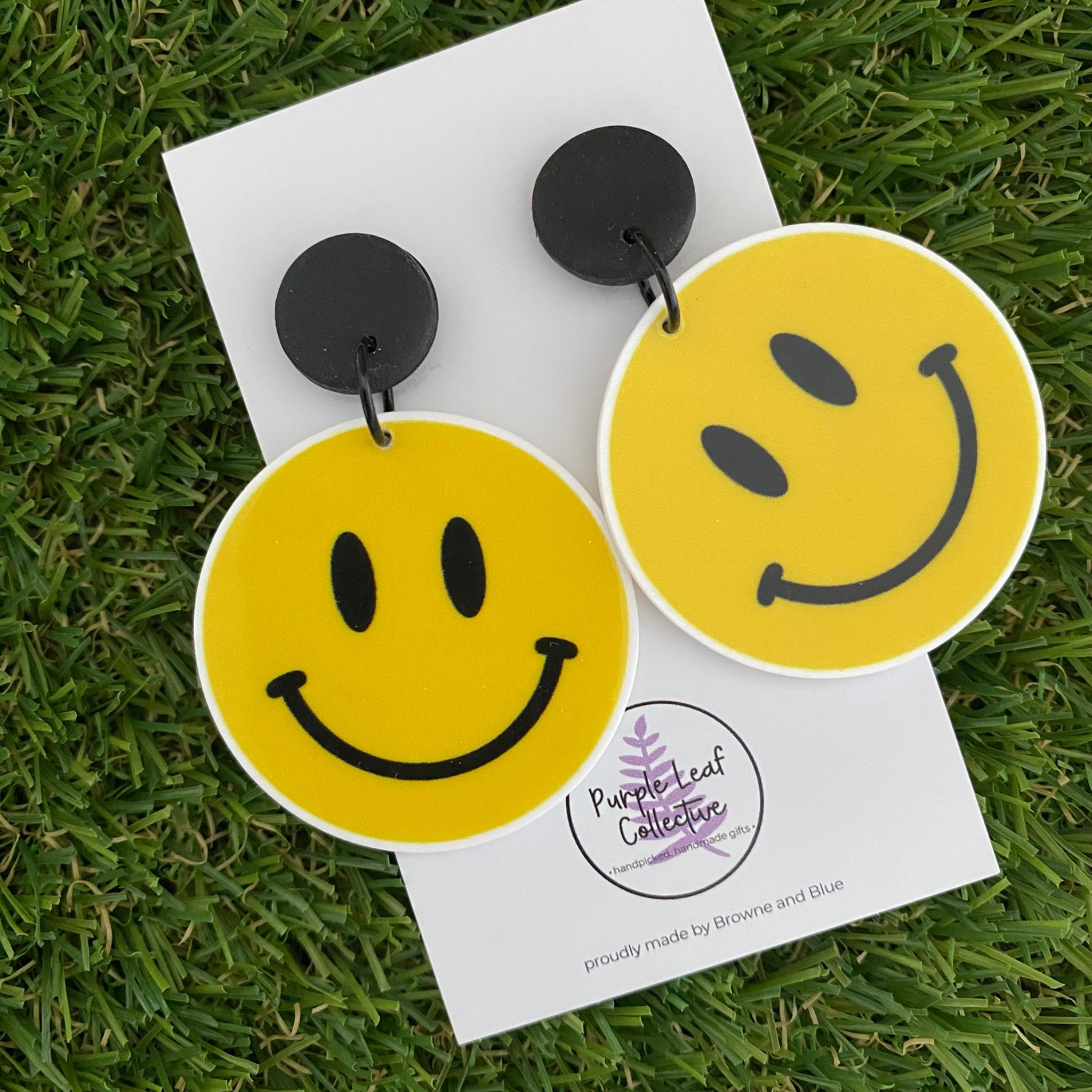 Yellow smiley face dangle earrings set on black stud tops.