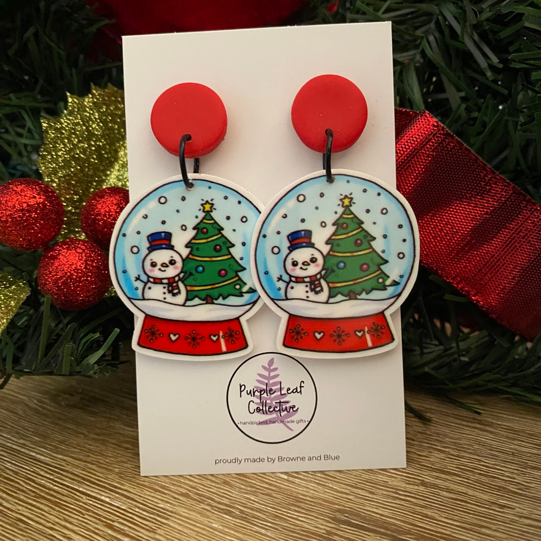 Christmas-themed earrings on a card with festive background.