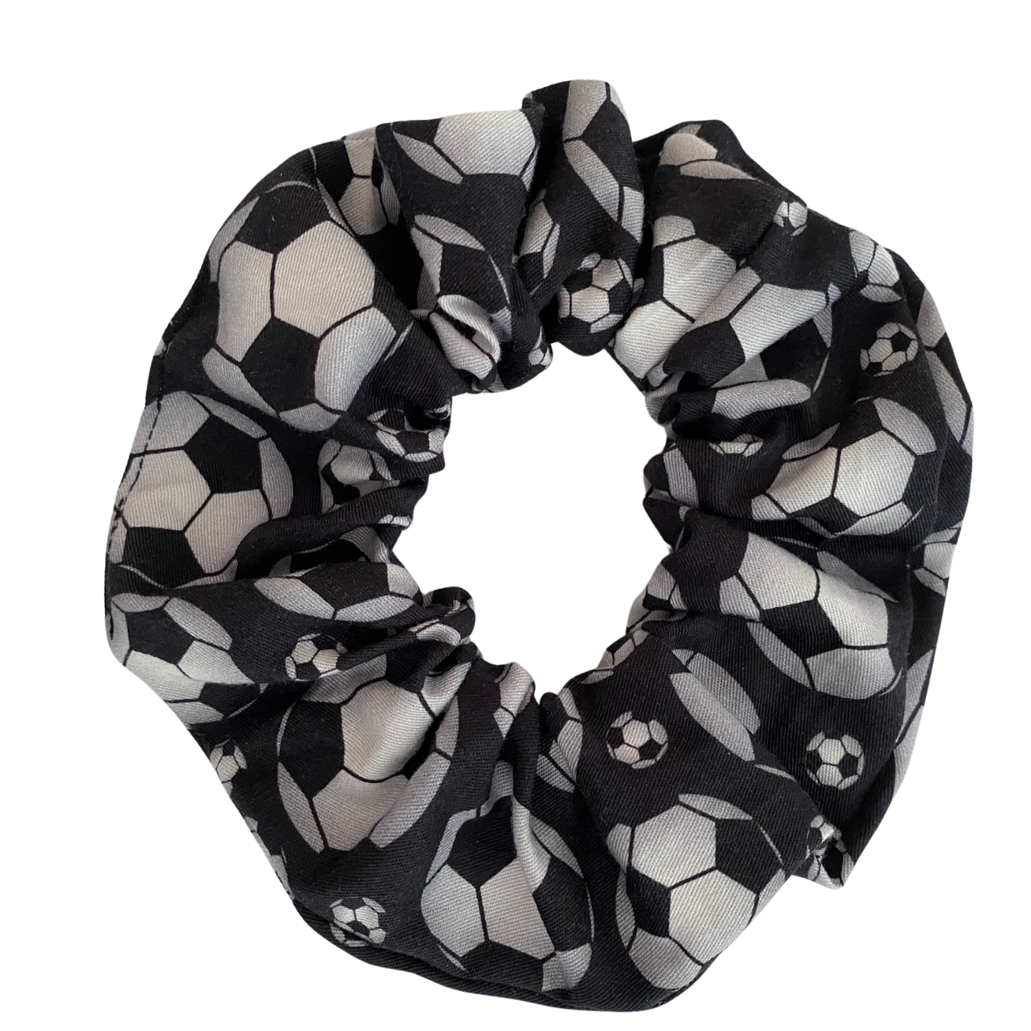 A scrunchie featuring images of soccer balls on a black fabric featuring durable braided elastic for secure styling.