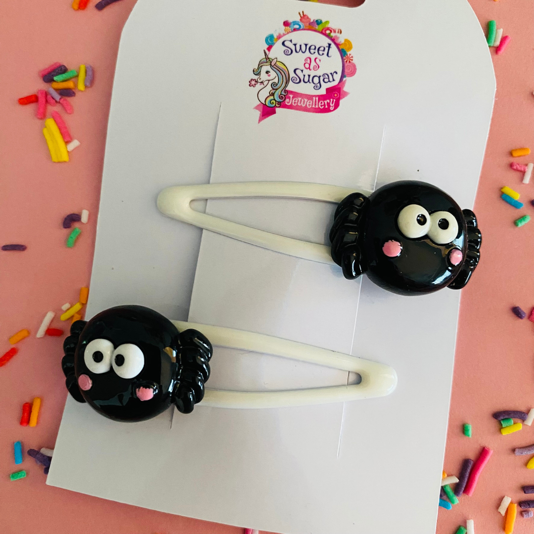 Spider hair clips feature an eight-legged black spider with eyes, set on a white hair clip.