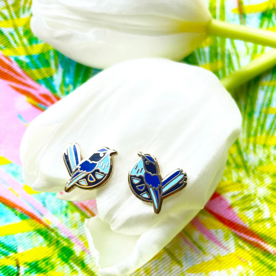 Blue bird-shaped earrings on a white surface with a colorful background.