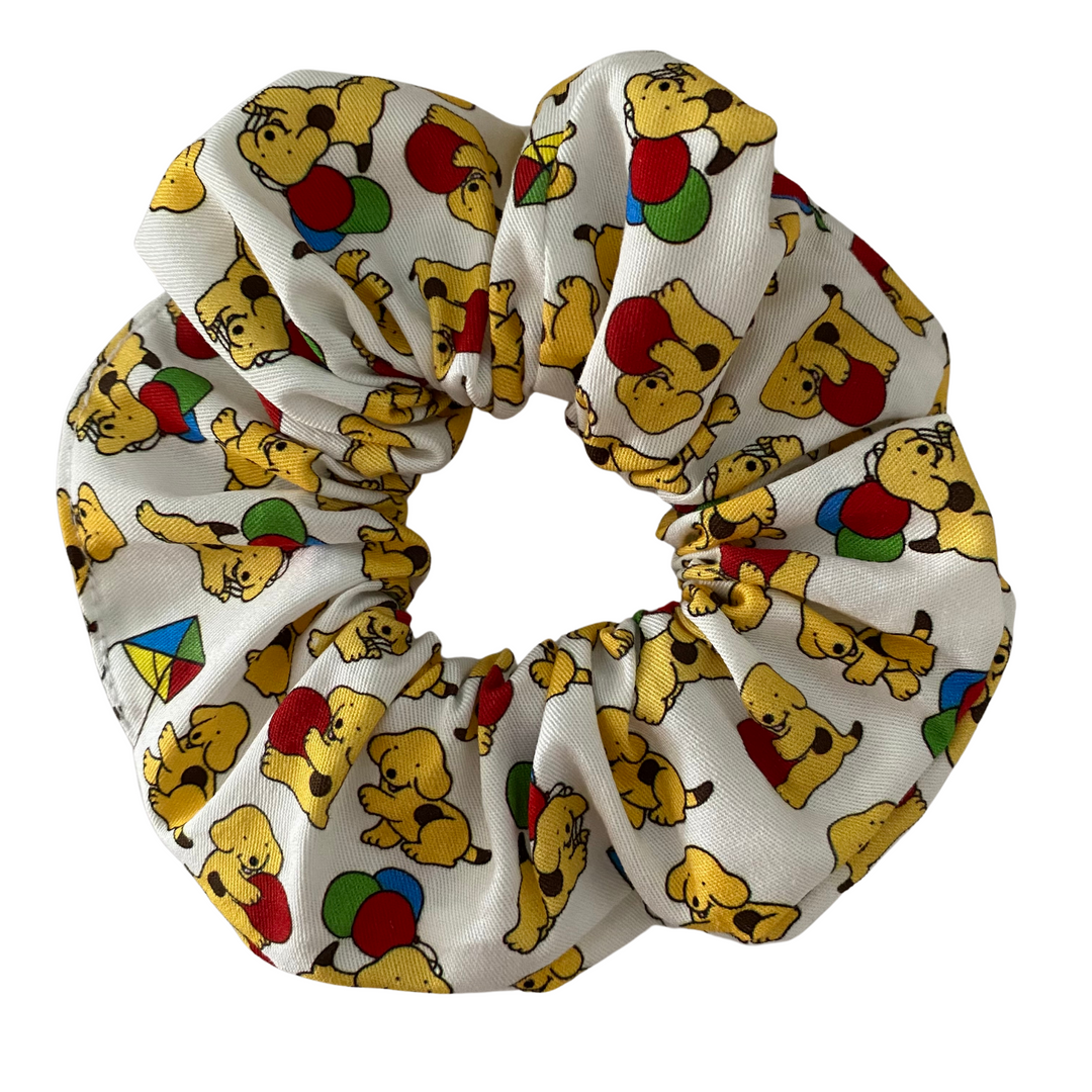 A picture of a scrunchie featuring cutes images of Spot the Dog with kites and balloons on a white fabric background.