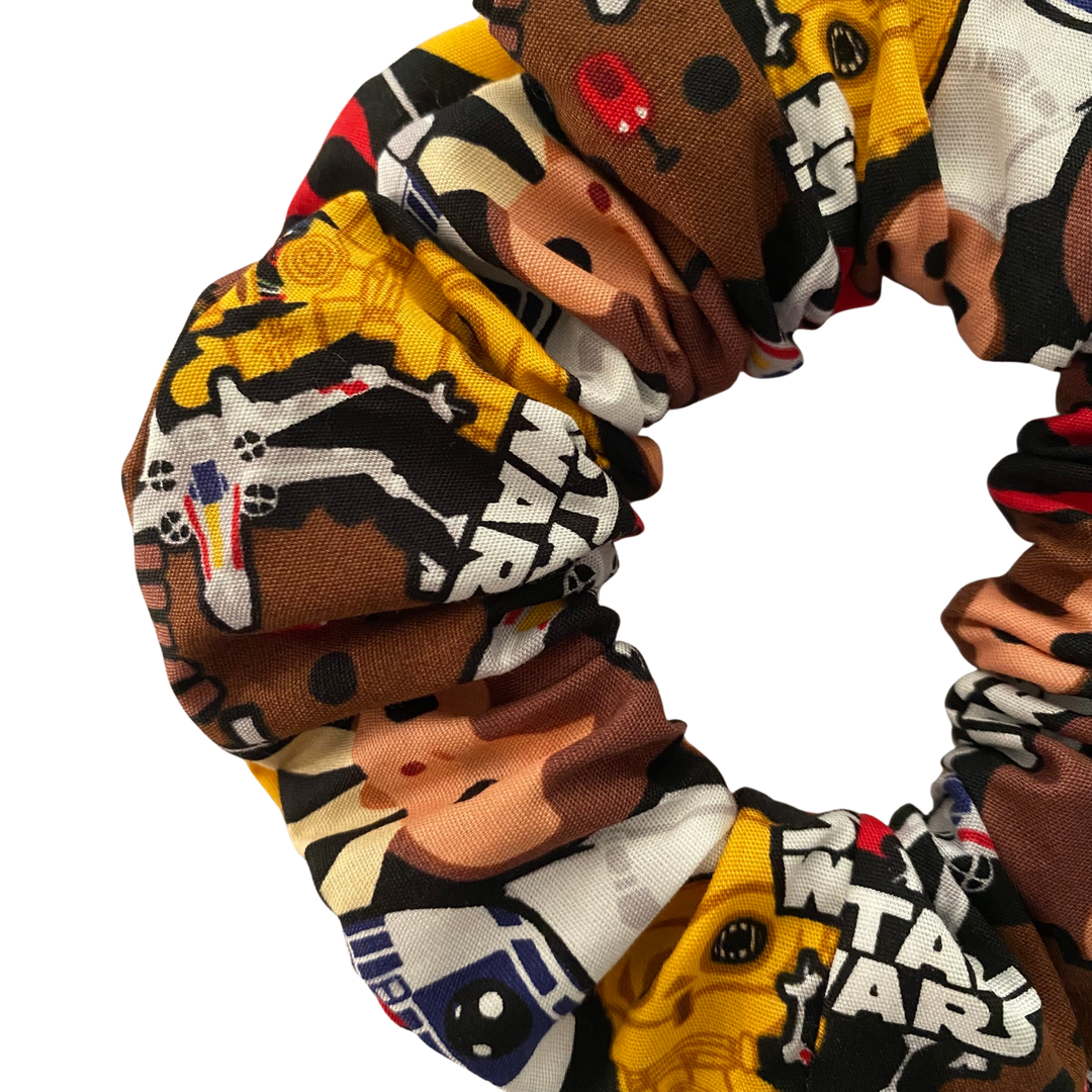 A close up view of a black fabric scrunchie with images of all your favourite Star Wars characters.