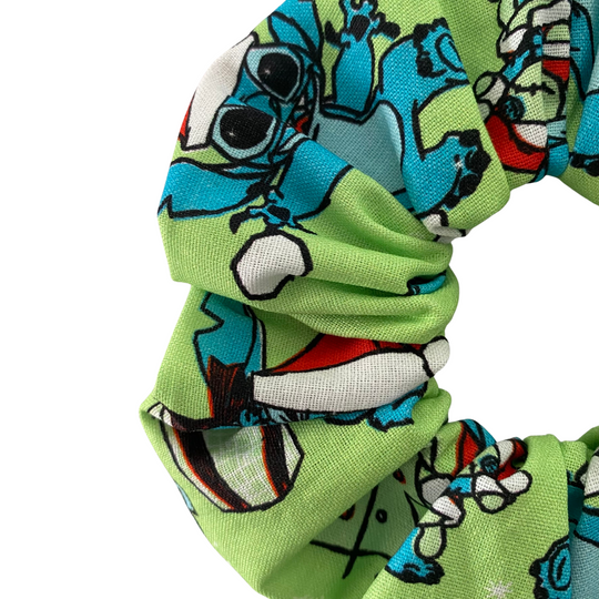 Close up view of a green scrunchie with Stitch character pattern on a white background.