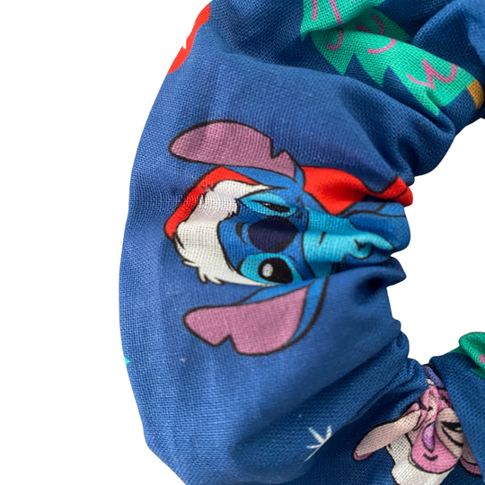Close up view of a blue scrunchie with colorful cartoon character pattern on a white background.
