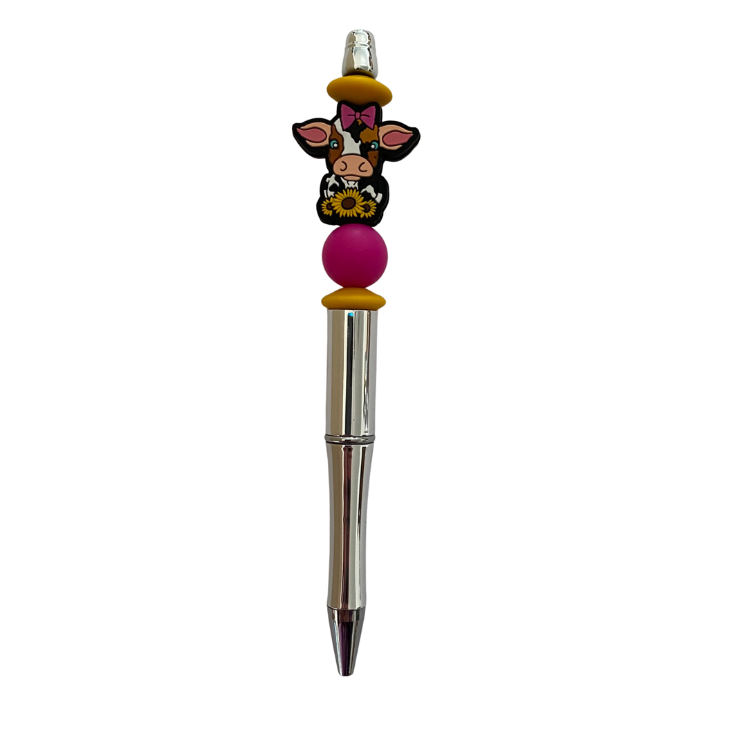 Pen with a sunflower cow silicone bead on top on a white background.