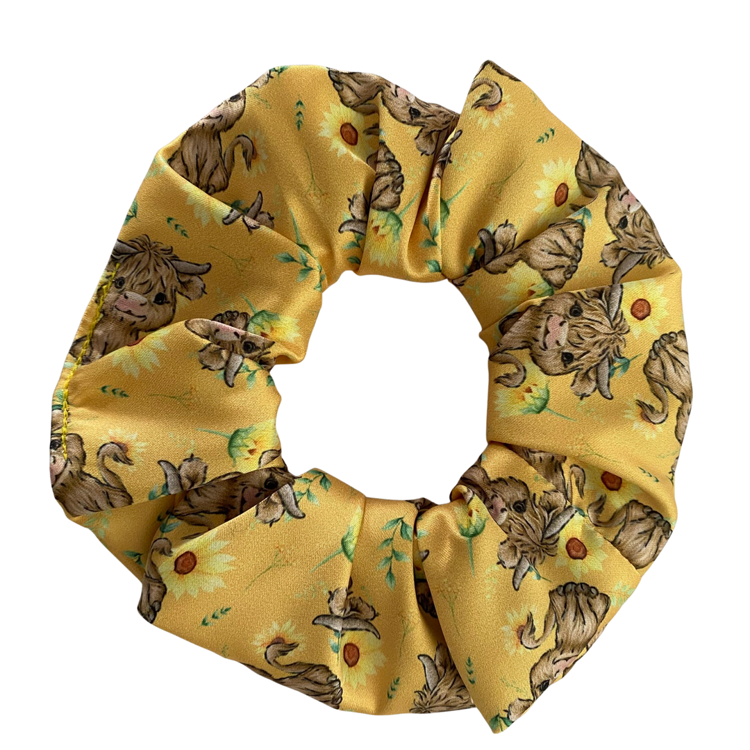 Yellow scrunchie with Highland cow pattern on a white background.