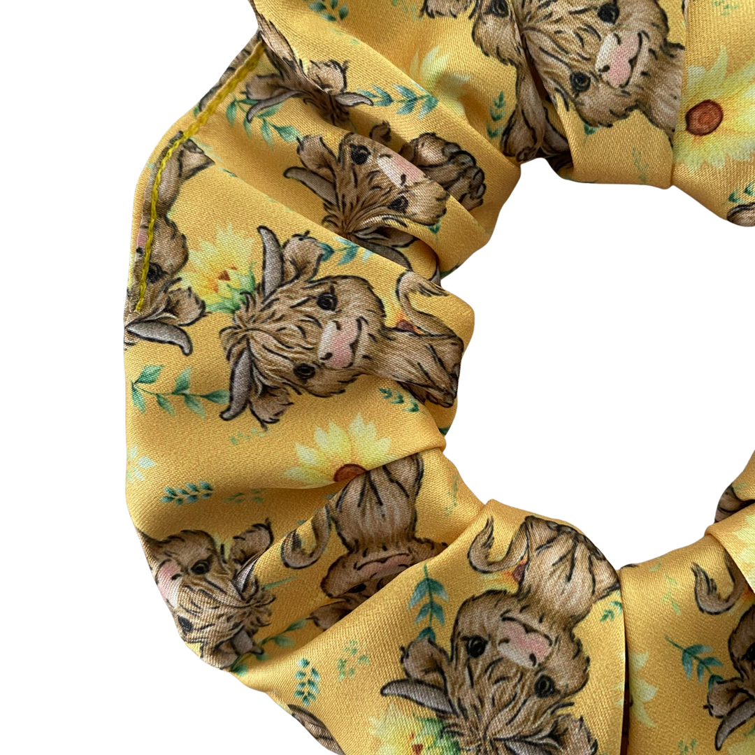 Yellow sunflower scrunchie with Highland cow pattern on a white background.