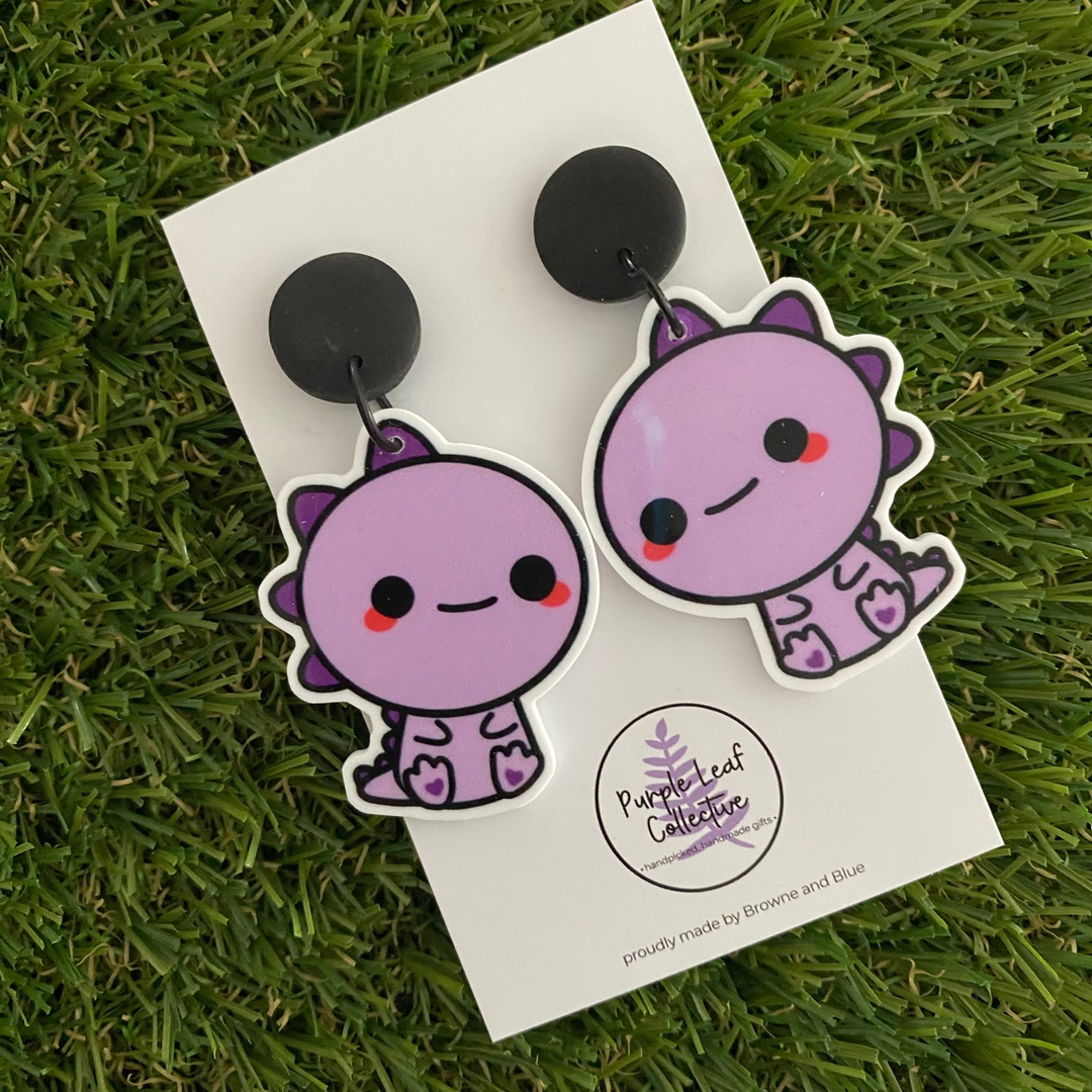 Pair of purple T-Rex dinosaur earrings set on black stud tops.