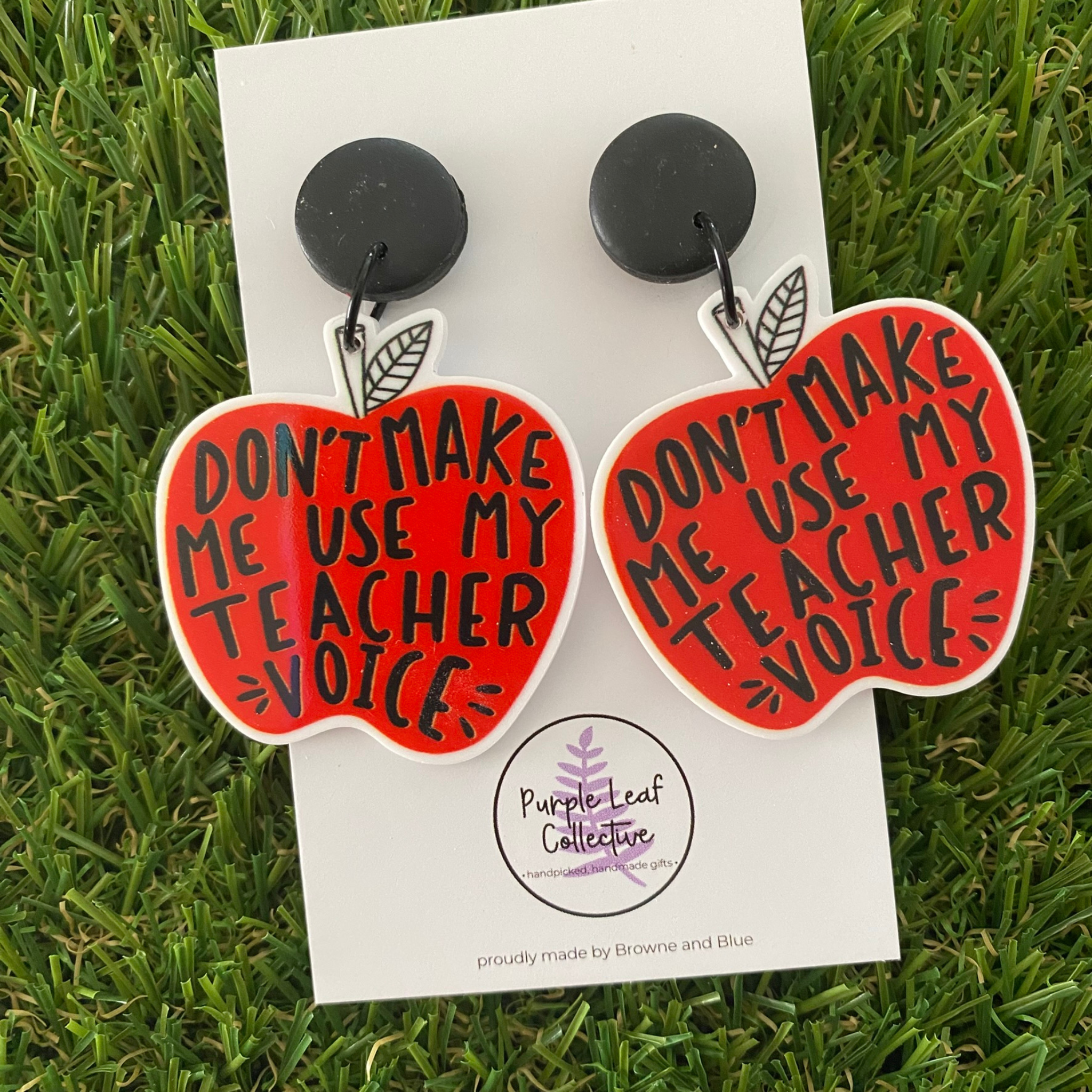 Red appled shaped earrings with the words Don't Make Me Use My Teacher Voice written on the red apples.