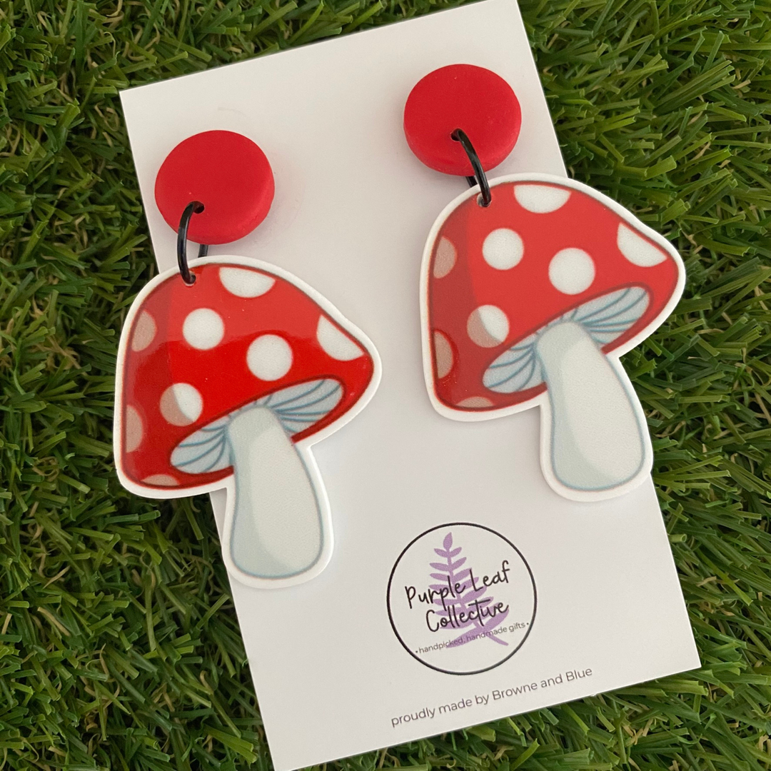 Red polka dot mushroom earrings set on red clay stud tops.