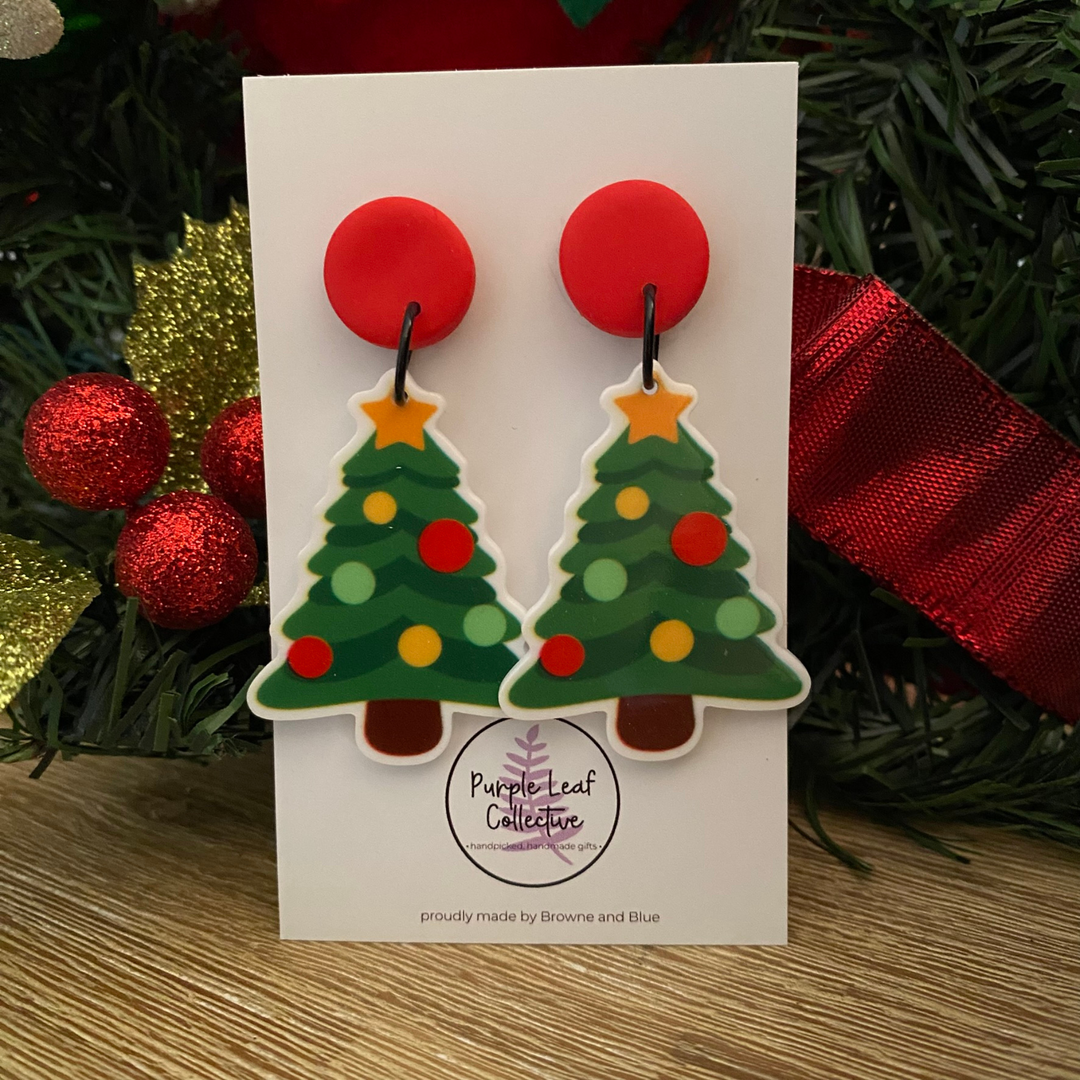 Christmas tree earrings on a card with festive background.
