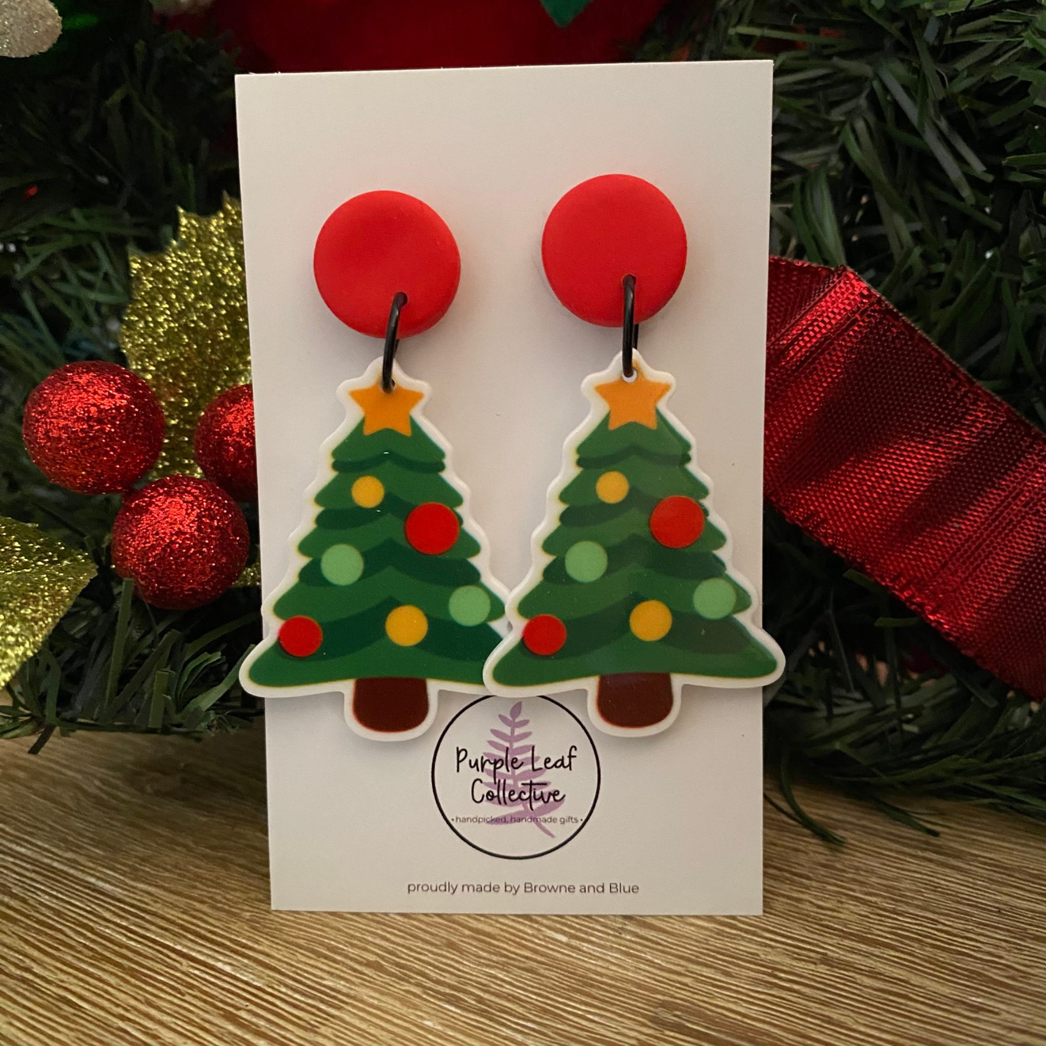 Christmas tree earrings on a card with festive background.