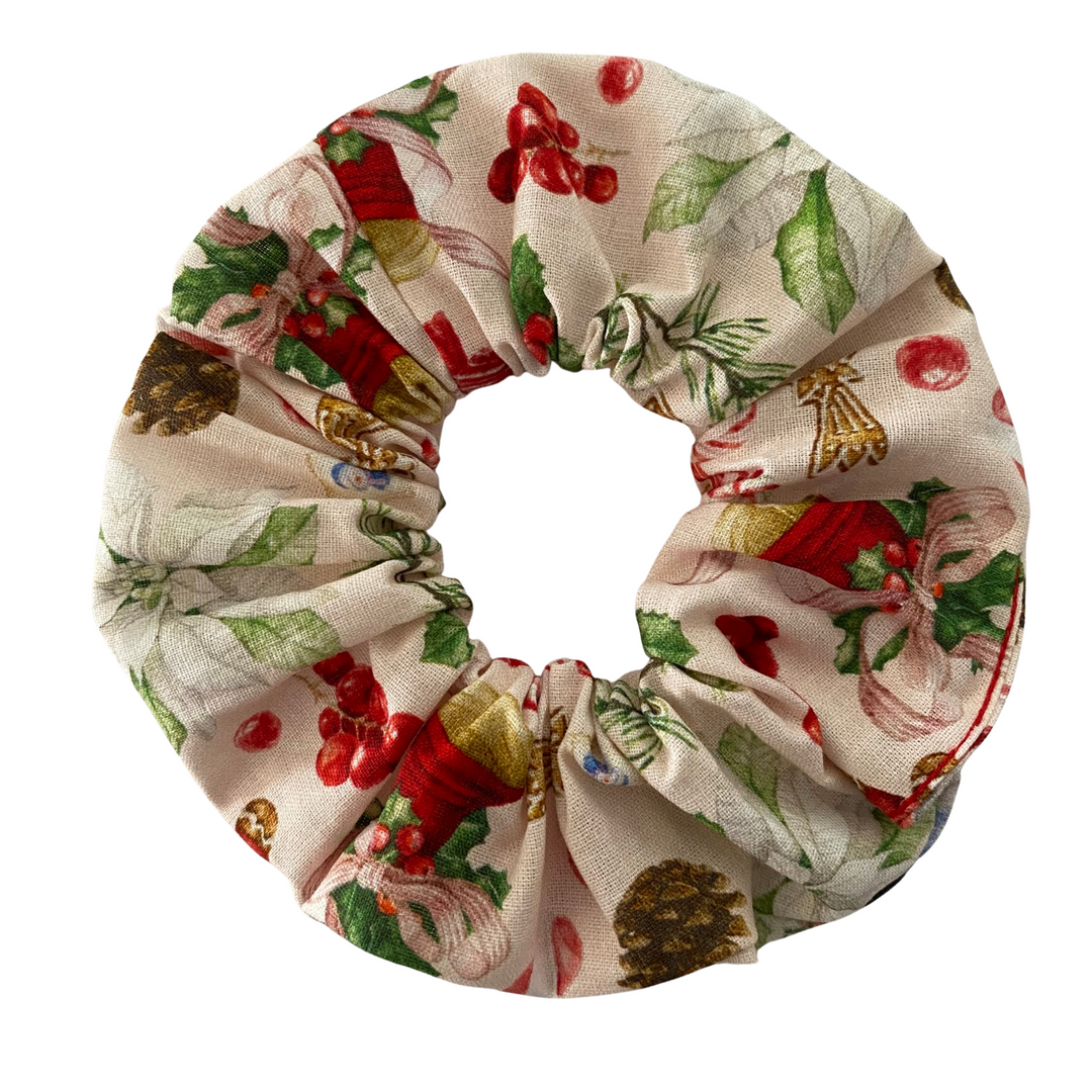 Christmas-themed scrunchie with red berries, holly leaves, and gold bells on a white background.