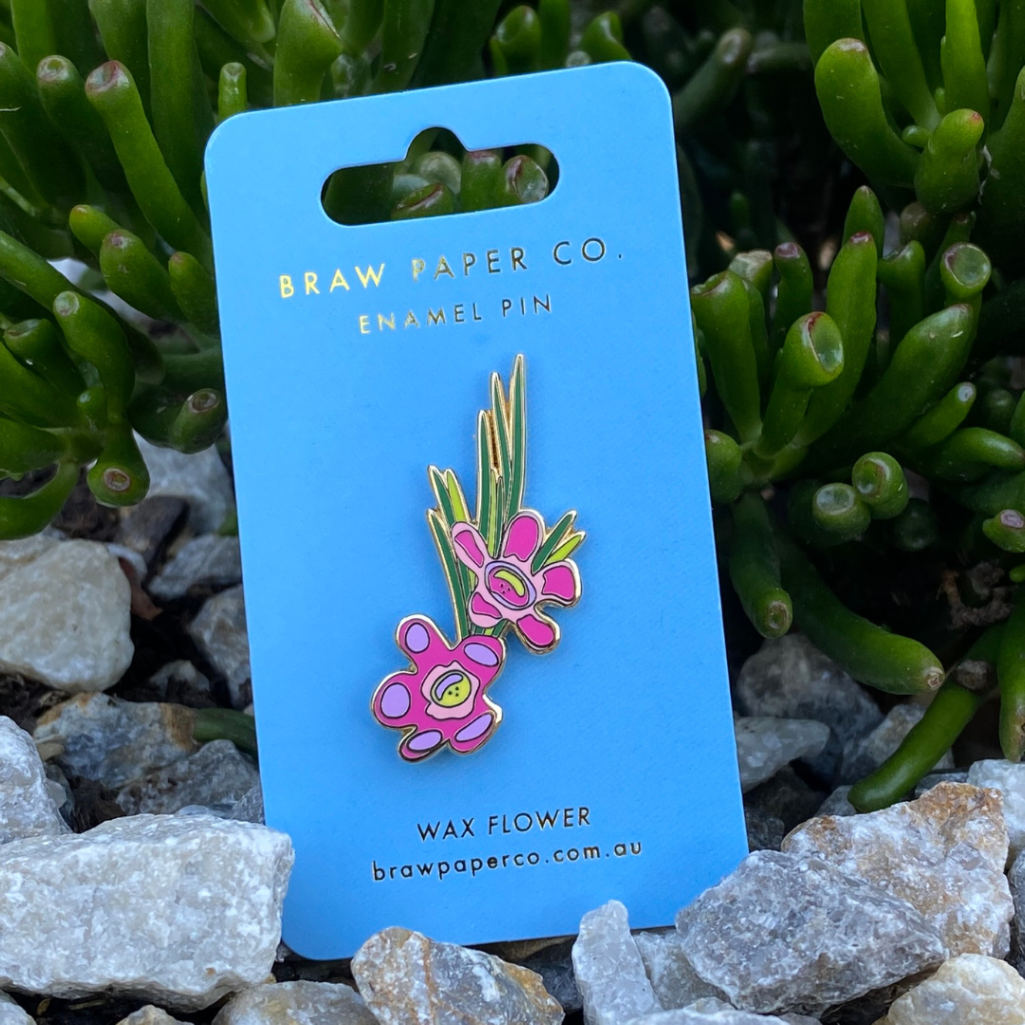 The Wax Flower Enamel Pin with pink flowers and green leaves.