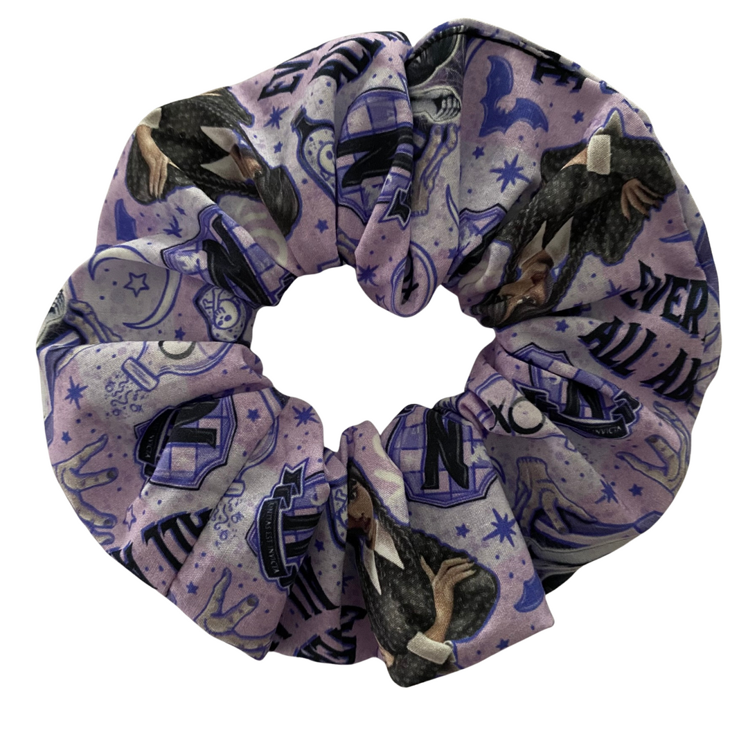 A purple scrunchie featuring images of Wednesday Addams on a white background.