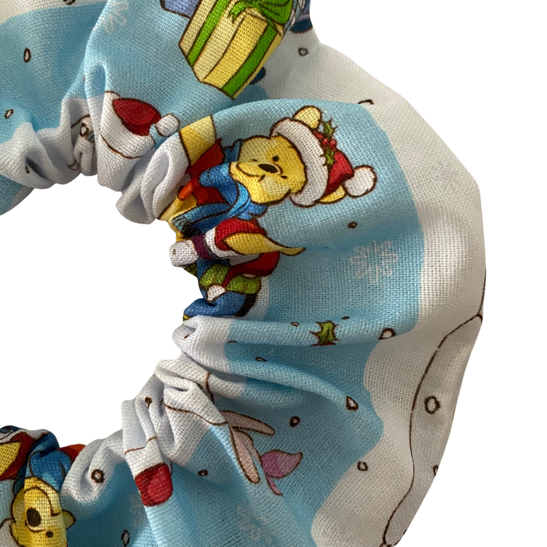 A snowy blue scrunchie with images of Winnie the Pooh, Tigger and Piglet.