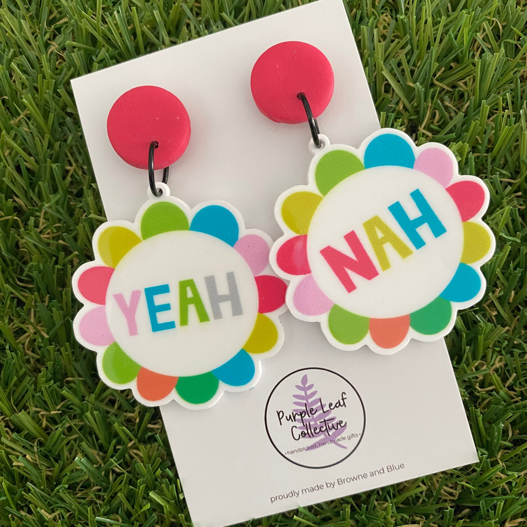 Colorful 'Yeah' and 'Nah' dangle earrings on a backing card.